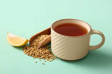 Cup of hot buckwheat tea with lemon on turquoise background