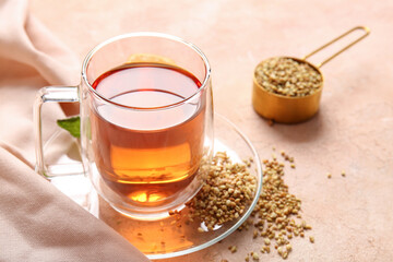 Glass cup of hot buckwheat tea on beige background