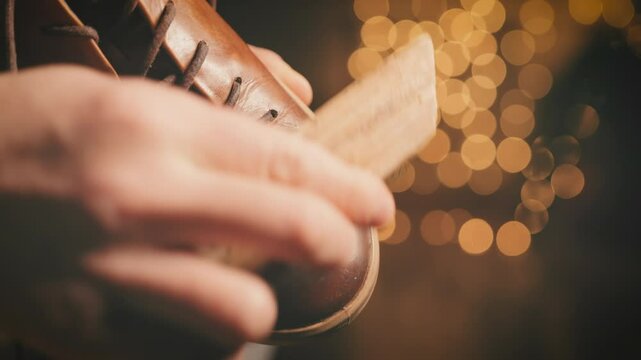 Brown leather shoe polishing macro shot with soft bokeh lights. Close-up of boot care and maintenance process with brush in warm lighting