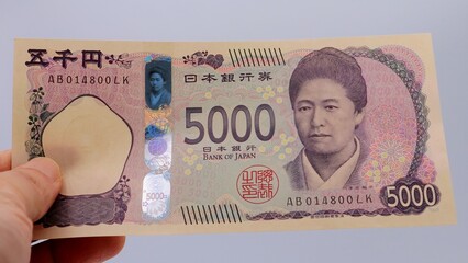 日本の新五千円札を持つ人物のクローズアップ
