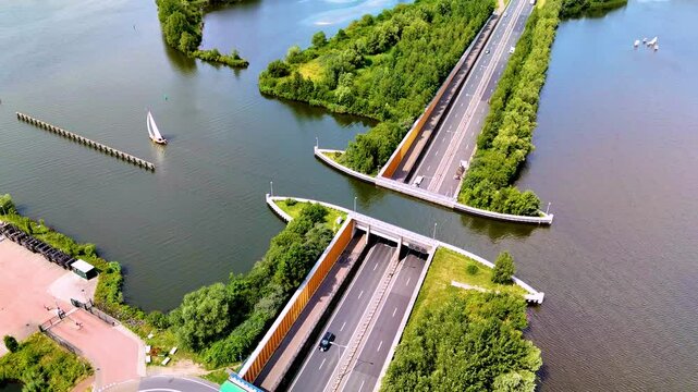 This captivating sight showcases the Veluwemeer Aqueduct Netherlands, where a highway elegantly crosses under a scenic waterway. Surrounded by lush greenery, this architectural marvel invites