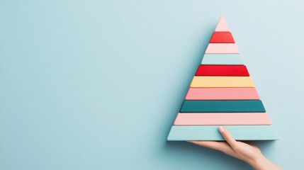 Fototapeta premium 2025 planning aligns with goal setting and objectives. Colorful wooden pyramid resembling a Christmas tree held against a blue wall.
