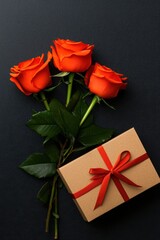 A charming gift box adorned with a vibrant red ribbon sits alongside three exquisite roses, embodying love and affection for Valentine's Day.