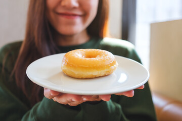 Closeup of a young woman holding a plate of donut