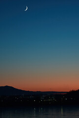 Obraz premium A fingernail moon rises over Wasilla, Alaska, at sunset.