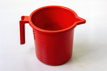 A red plastic mug on a light wooden surface.