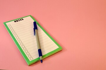 notepad and pen on pink background