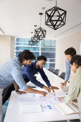 Busy multiethnic business group discussing marketing reports at meeting table, analyzing statistic...