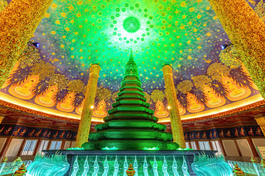 Temple with emerald-green glass pagoda. Buddhist temple of Wat Paknam Phasi Charoen, Bangkok, Thailand. Marble floor, ornate gilded columns and brightly decorated domed ceiling. 
