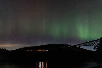 Bridge silhouetted by Northern Lights along coast from Deception Pass State Park on Whidbey Island in Washington 
