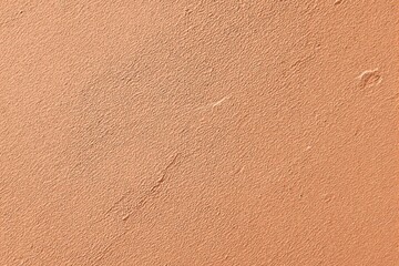Fototapeta premium Close-up of rough-textured orange wall surface, natural light enhances the detail, ideal for background or design concepts. Ai generative