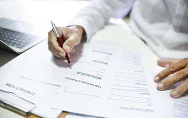 Blur hand of asian man reading contract making deal with life insurance agent before sign. concept...