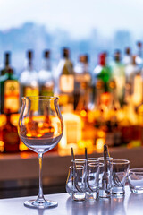 Wine and Drink glasses are arranged in front of drinks counter  bar with cityscape background