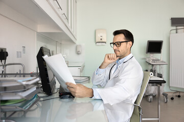 Serious professional ultrasonographer doctor reviewing ultrasound scan result, reading medical...
