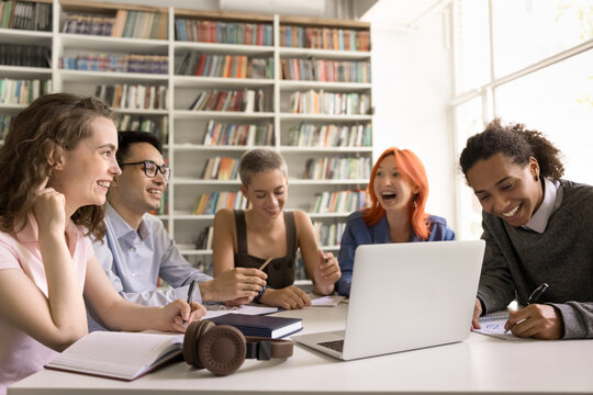 Education on distance. Happy friendly diverse group polyethnic students teenagers learn remotely at public library attend virtual class using computer app laugh on prof joke handwrite lecture theses - Powered by Adobe
