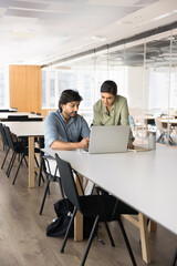 Two young Indian managers working on online business project together, using laptop for Internet communication, discussing Internet marketing strategy, cooperation, partnership