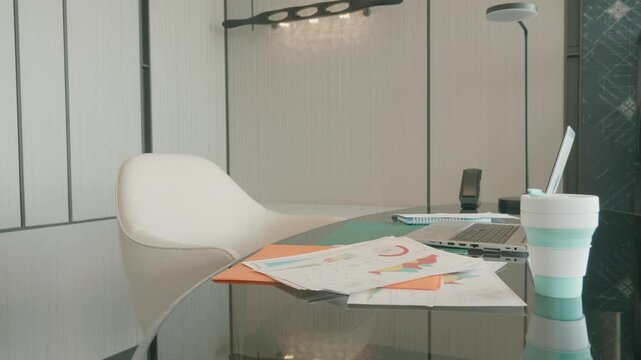 A contemporary workspace featuring a laptop, scattered documents, and a comfortable chair. Ideal for productivity and focus, this setup is perfect for remote work, studying, or creative projects.
