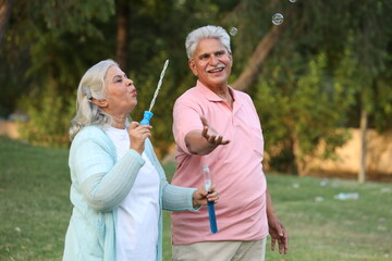 Fototapeta premium Indian happy Senior couple playing bubbles in garden
