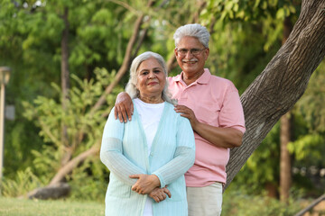 Indian happy senior beautiful couple embracing tohether and looking romantic and close together in garden