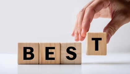 Hand placing the letter T on a block spelling BEST in focus.