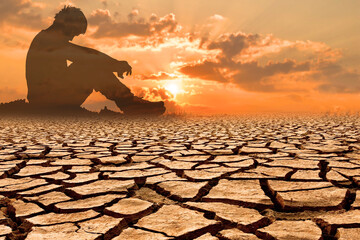 Silhouette of a Person Sitting on Cracked Earth at Sunset Symbolizing Climate Change and...