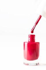 Nail bottle brush drops the nail polish liquid into the bottle on white background