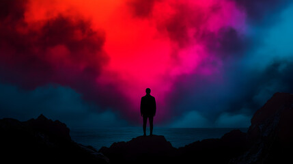 Businessman silhouetted on rocky coastline, gazing toward vibrant sunset sky blending crimson, pink, and azure, embodying contemplative moment of professional reflection