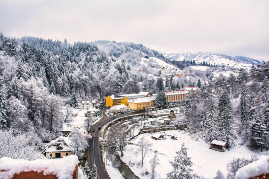 Snowy winding road traversing sovata resort in harghita county, romania, with snow-laden landscape, vehicles navigating winter scenery