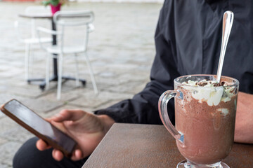 Young Man Sitting in a Cafe, Using His Smartphone