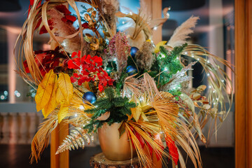 A vibrant decorative floral arrangement with dried leaves, red and gold accents, blue ornaments,...
