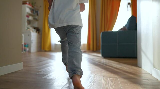 Mother playing with son at home. Son run towards mother sitting on floor. Happy family bonding. Bright cozy room. Mother and son enjoying playful time together. Son run mother at home. happy family