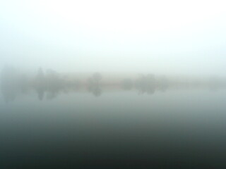 Fototapeta premium Mining pond in the Harz in the fog. A mystical mining pond in the Harz. Fog, reflections, and horizons in winter create an enigmatic atmosphere, perfect for diverse themes.