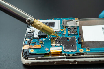 Technician repairing inside of mobile phone by soldering iron. Integrated Circuit. the concept of...