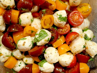 Tomato salad with mozzarella balls, yellow and red cocktail tomatoes, fresh basil. The format-filling photo is for food designs and scenes.