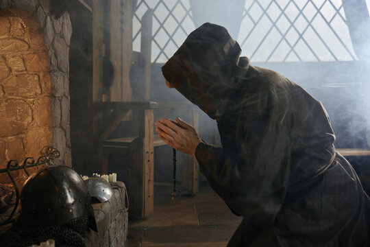 Desperate priest kneeling before church altar in mystical smoke