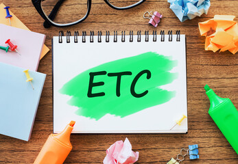 text ETC abbreviation of et cetera written on notepad on wooden background