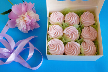 A white box filled with colored meringue cookies, Gift box of Zefir, Zephyr and flowers. A gift box of zephyr - marshmallow and peonies flowers.