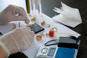 A pawn shop employee tests old gold jewelry using reagents and a touchstone, Buying old gold, closeup