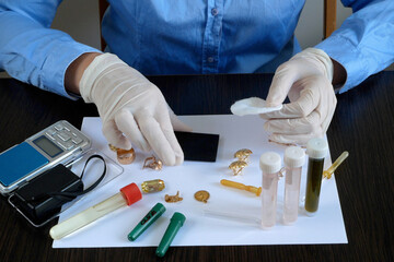 A pawn shop employee tests old gold jewelry using reagents and a touchstone, Buying old gold,...