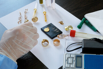 A pawn shop employee tests old gold jewelry using reagents and a touchstone, Buying old gold,...