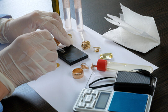 A pawn shop employee tests old gold jewelry using reagents and a touchstone, Buying old gold, closeup