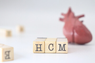 HCM letters written on wooden blocks isolated with heart on white background. Hypertrophic Cardiomyopathy concept of cardiology disease
