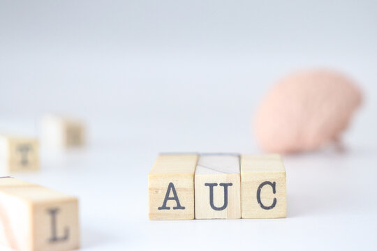 Acronym for automatic learning AUC. Area Under the Curve written on wooden cubes isolated with a brain on a white background with copy space.