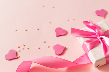 Fototapeta premium Pink hearts and gift box with ribbon on a light pink background