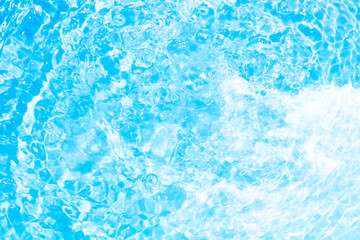 Blue water with ripples on the surface. Defocus blurred transparent blue colored clear calm water surface texture with splashes and bubbles. Water waves with shining pattern texture background.