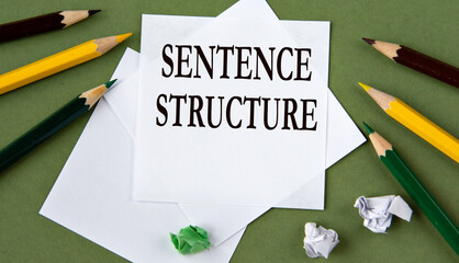 SENTENCE STRUCTURE - words on white paper on a green background with pencils