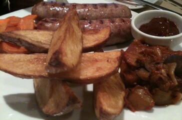 Sausage, pickles and French fries in white plate