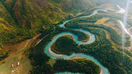 Aerial view of a turquoise river winding through a vibrant green forest. Creating stunning loops...