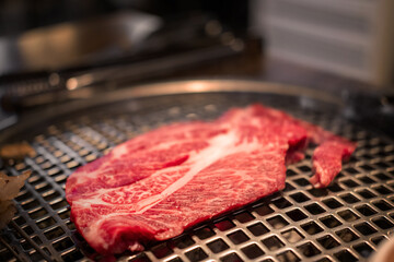 A close-up shot of premium cuts of marbled Hanwoo beef, Korean Style Meat on the Grill. BBQ rare meat with soft focus