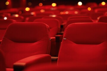 Obraz premium Close-up of red theater seats, warm bokeh lights in the background, cinematic ambiance, on a dark background, concept of entertainment. Ai generative